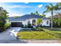 White house with dark gray roof, landscaping, and a black garage door at 11124 Hyacinth Pl, Lakewood Ranch, FL 34202