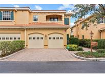 Tan two-story townhome with two-car garage and manicured landscaping at 3665 Square West Ln # 13, Sarasota, FL 34238