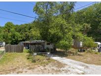 Modest home situated on a lot with mature trees and overgrown lawn at 9127 Bourbon St, New Port Richey, FL 34654