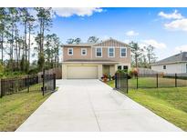 Two-story house with a tan exterior, black fence, and landscaped front yard at 1379 E Price Blvd, North Port, FL 34288