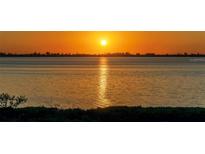 Orange sunset over the water with city skyline in the distance at 4600 Gulf Of Mexico Dr # 206, Longboat Key, FL 34228