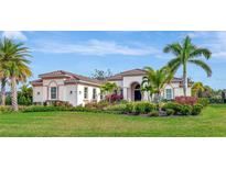 Single-story home with tile roof, landscaping, and palm trees at 4986 Antiquity Way, Sarasota, FL 34240