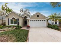 Tan house with white garage door, landscaping, and brick driveway at 96 Tall Trees Ct, Sarasota, FL 34232
