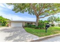 Tan brick ranch house with lush landscaping and large tree in front at 2502 Alpine Ave, Sarasota, FL 34239