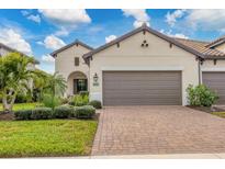 Two-story house with brown garage door and landscaped yard at 26954 Pavin Dr, Englewood, FL 34223