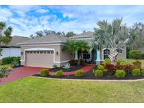 Tan house with red driveway, landscaping, and palm trees at 12338 Lavender Loop, Bradenton, FL 34212