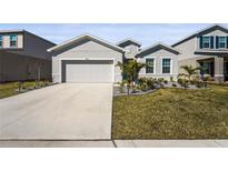 Single-story home with gray siding, two-car garage, and landscaped lawn at 9810 Eventide Trl, Parrish, FL 34219