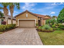 Tan house with tile roof, paver driveway, and landscaped yard at 12785 Fontana Loop, Bradenton, FL 34211