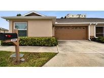 Front view of a tan house with a brown garage door and neatly landscaped yard at 2906 Captains Ct, Palmetto, FL 34221