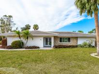 White single story home with stone accents and a lush green lawn at 5560 Shadow Lawn Dr, Sarasota, FL 34242