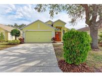 Bright yellow house with a two-car garage and well-manicured lawn at 6215 Blueflower Ct, Lakewood Ranch, FL 34202