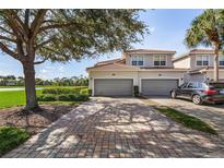 Lovely townhome with a brick driveway leading to two-car garages, complemented by lush landscaping and serene lake views at 14081 Black Beauty Dr # 1111, Punta Gorda, FL 33955