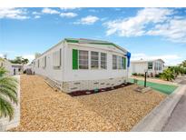 White single-wide mobile home with green accents and landscaped yard at 2107 Palma Sola Blvd # 13, Bradenton, FL 34209