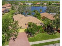 Spacious home featuring tile roof, lush landscaping, and a brick driveway, near a lake at 4850 Sweetshade Dr, Sarasota, FL 34241