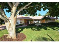 Beautiful home exterior featuring a landscaped yard, fountain, and mature tree at 521 Wedge Ln, Longboat Key, FL 34228