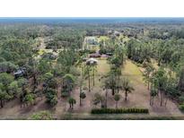 Aerial view showing a house on a spacious lot with surrounding trees and pasture at 3340 Ulman Ave, North Port, FL 34286