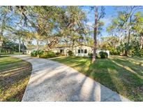 Charming single-story home featuring a lush green lawn, mature trees, and a long driveway at 3501 Sunbeam Dr, Sarasota, FL 34240