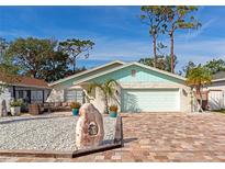 Updated home with light teal accents, a gravel yard, and a brick paver driveway at 4534 Pike Ave, Sarasota, FL 34233