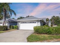 House exterior featuring a white garage door, landscaping, and a paved driveway at 5532 Country Club Way, Sarasota, FL 34243