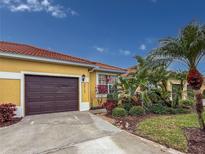 Well-maintained house with a brown garage door, landscaping, and palm trees at 5715 Spanish Point Ct, Palmetto, FL 34221