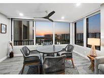 Bright dining area features floor to ceiling windows with sunset views and modern gray dining set at 5780 Midnight Pass Rd # 609, Sarasota, FL 34242