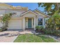 Two-story house with light yellow walls, green door, and a two-car garage at 1110 Beachcomber Ct # 1, Osprey, FL 34229