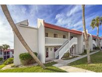 Two-story condo building with red roofs, white walls, and palm trees at 1801 Gulf N Dr # 121, Bradenton Beach, FL 34217