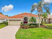 Single-story home with a red tile roof, two-car garage, and landscaped lawn at 5062 Flagstone Dr, Sarasota, FL 34238