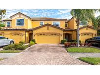 Two-story townhome with yellow exterior, two-car garage, and landscaped front yard at 8115 Miramar Way # 202, Lakewood Ranch, FL 34202