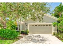 Tan house with two-car garage and lush landscaping at 11662 Old Cypress Cv, Parrish, FL 34219