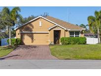 One-story house with tan exterior, brick driveway, and landscaping at 2200 Pratt Avenue, North Port, FL 34286