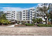 Exterior view of a modern white condo building with landscaped grounds and a covered entrance at 2550 Harbourside Dr # 322, Longboat Key, FL 34228