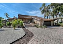 Inviting exterior featuring a tile roof, palm trees, beautiful landscaping, brick driveway, and attached garage at 3131 Bayou Sound, Longboat Key, FL 34228
