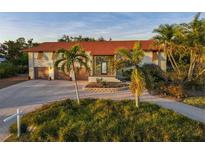 Charming home featuring a red roof, lush landscaping, and a welcoming entrance, complemented by a paved driveway and palm trees at 424 Cezanne Dr, Osprey, FL 34229