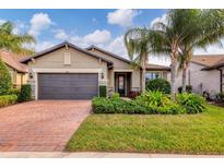 Single-story home with a two-car garage and landscaped yard at 11241 Sandhill Preserve Dr, Sarasota, FL 34238