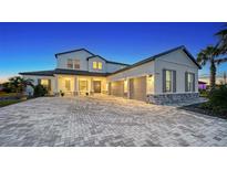 Two-story home with gray accents, paver driveway, and palm trees at 15009 18Th E Run, Parrish, FL 34219