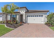 One-story home with white garage door, paver driveway, and tropical landscaping at 2114 5Th E St, Palmetto, FL 34221