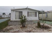 White single-wide mobile home with carport and small landscaped yard at 232 Trailorama Dr, North Port, FL 34287