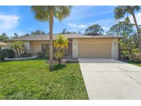 Tan house with a two-car garage and palm trees in the front yard at 4410 Little John Trl, Sarasota, FL 34232