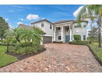Stately home with brick drive, lush landscaping, and a striking blue entry door at 13408 Swiftwater Way, Bradenton, FL 34211