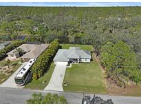 An aerial view of the house with a long drive, large yard and backing onto a pond and extensive woodland at 3151 Johannesberg Rd, North Port, FL 34288