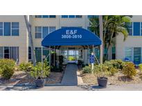 Condo building entrance with awning, walkway, and landscaping at 3810 Gulf Of Mexico Dr # F302, Longboat Key, FL 34228