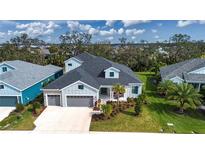 Aerial view of a charming house with a gray roof and light blue exterior, surrounded by lush landscaping at 4304 Fly Rod Ter, Parrish, FL 34219