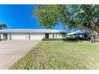 Front view of charming villa with 2-car garage, lush lawn and mature tree at 6704 11Th W Ave, Bradenton, FL 34209