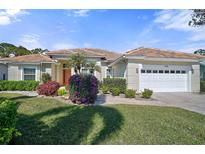 Single-story home with a tile roof, attached garage, and lush landscaping at 1985 White Feather Ln, Nokomis, FL 34275