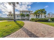 Two-story house with paver driveway, lush landscaping, and palm trees at 634 Key Royale Dr, Holmes Beach, FL 34217