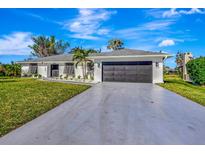 Newly renovated home with a modern dark gray garage door and lush landscaping at 1608 Honey Ct, Venice, FL 34293