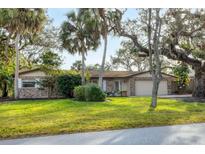 Brick ranch house with mature landscaping and large oak trees at 1947 W Leewynn Dr, Sarasota, FL 34240