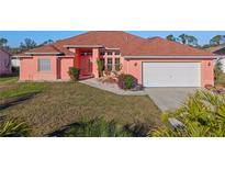 Attractive coral home with a two-car garage and well-manicured lawn at 2421 Palomar St, North Port, FL 34287