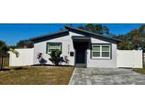 Modern single story home with gray exterior, paver driveway, and white fence at 4029 9Th S Ave, St Petersburg, FL 33711